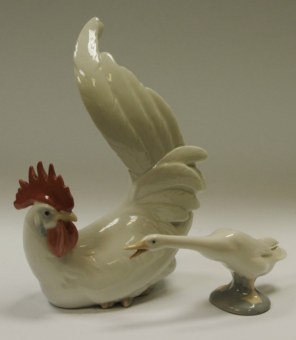 A Lladro porcelain model of a cockerel neutral tones, seated with tail raised, 9" (22.