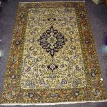 A Kashan rug, floral patterns in taupe, green and indigo on a cream ground.