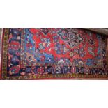 An Iranian hand knotted carpet, in tones of red, blue and yellow,