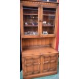 An Ercol bookcase, glazed doors enclosing adjustable shelves above a pair of cupboard doors, 196.
