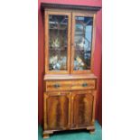 A reproduction mahogany bookcase, dentil cornice above a pair of glazed doors,