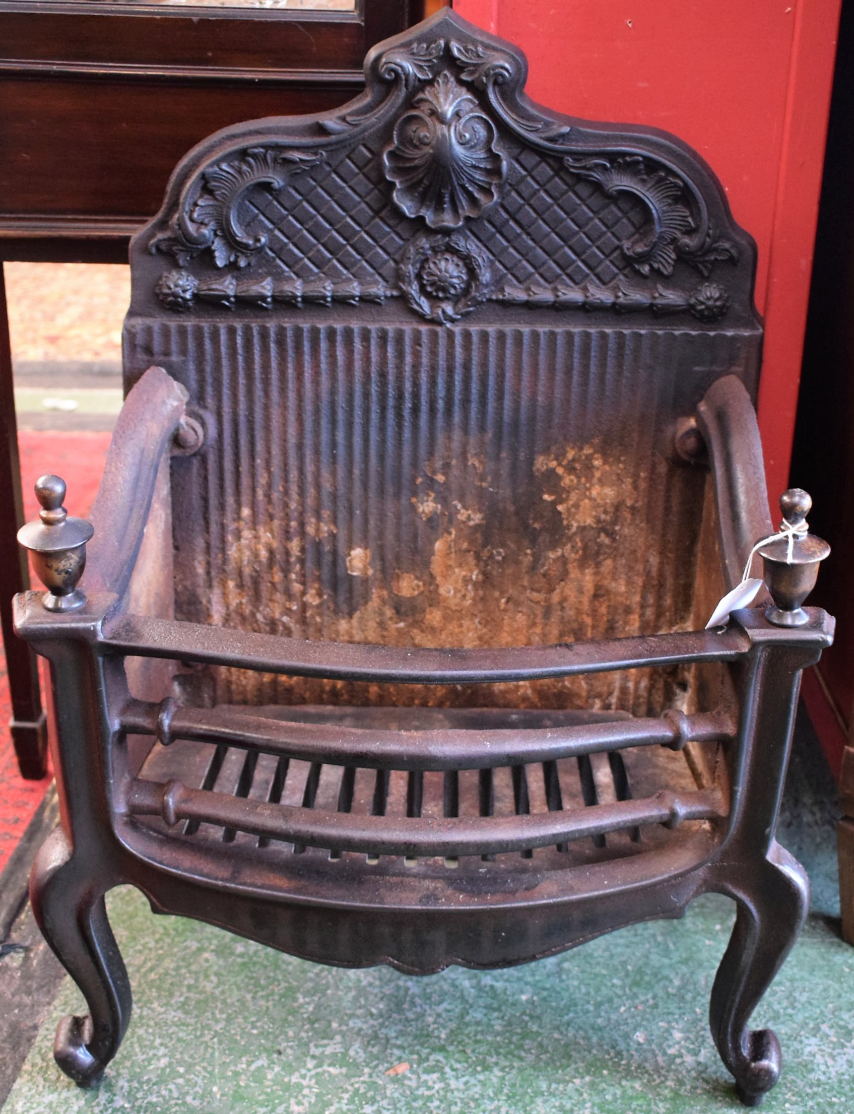 A 20th century cast iron fire basket, shaped cresting cast with a shell, rose,