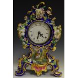 A porcelain mantel clock profusely decorated with colourful flora on cobalt ground.