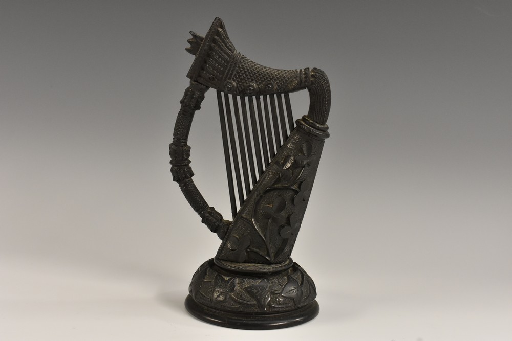 A 19th century Irish bog oak model, of a harp, carved with shamrocks, domed circular base,