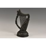 A 19th century Irish bog oak model, of a harp, carved with shamrocks, domed circular base,