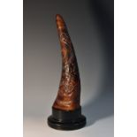 A Chinese horn, in relief with ferocious dragons chasing a flaming pearl, ebonised plinth,