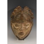 Tribal Art - an African mask, carved coiffure, eliptical features, traces of white pigment,