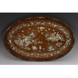 A Chinese hardwood oval panel, inlaid in mother of pearl with a figure on horseback,
