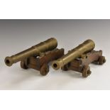 A pair of bronze desk model cannons, each oak carriage with four wheels, 33.