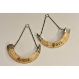 A pair of Anglo-Indian silver mounted boar tusk wine labels, Port and Madeira,