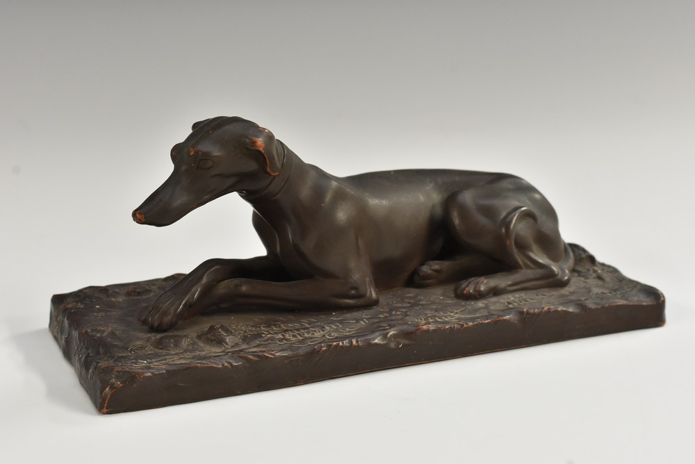 A 19th century Continental painted terracotta canine model, of a recumbent greyhound,