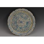 A Persian tin glazed earthenware shaped circular dish,