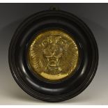 A 19th century gilt metal circular boss, in relief with the face of a ferocious tiger, 18cm diam,