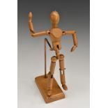 A beech artist's lay figure, typically articulated and mounted on a stand, rectangular base,