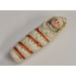 A 19th century German porcelain novelty whistle, as a swaddled baby, 7.5cm long, c.