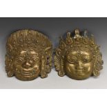 An Indian brass mask, embossed with the face of a deity, 23cm wide; another,
