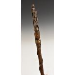 A folk art walking cane, the pommel carved as a seated figure,