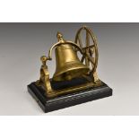 An early 20th century novelty table bell, as a church bell and wheel, rectangular ebonised base,