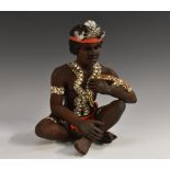 An Australian terracotta figure, of an Aborigine, seated cross-legged, holding a boomerang,