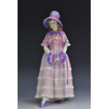 A Royal Doulton figure Estelle, she stands in poke bonnet and hand muff,