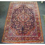 A Hand Made Jojan Rug, floral designs in salmon, taupe and cobalt on a red ground 150cm x 105cm.