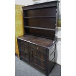 An Oak Dresser, shaped uprights and shelves to top, two drawers over two door cupboards to base.