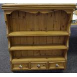 A country pine wall mounted shelving unit, shaped uprights, three shelves over three short drawers,