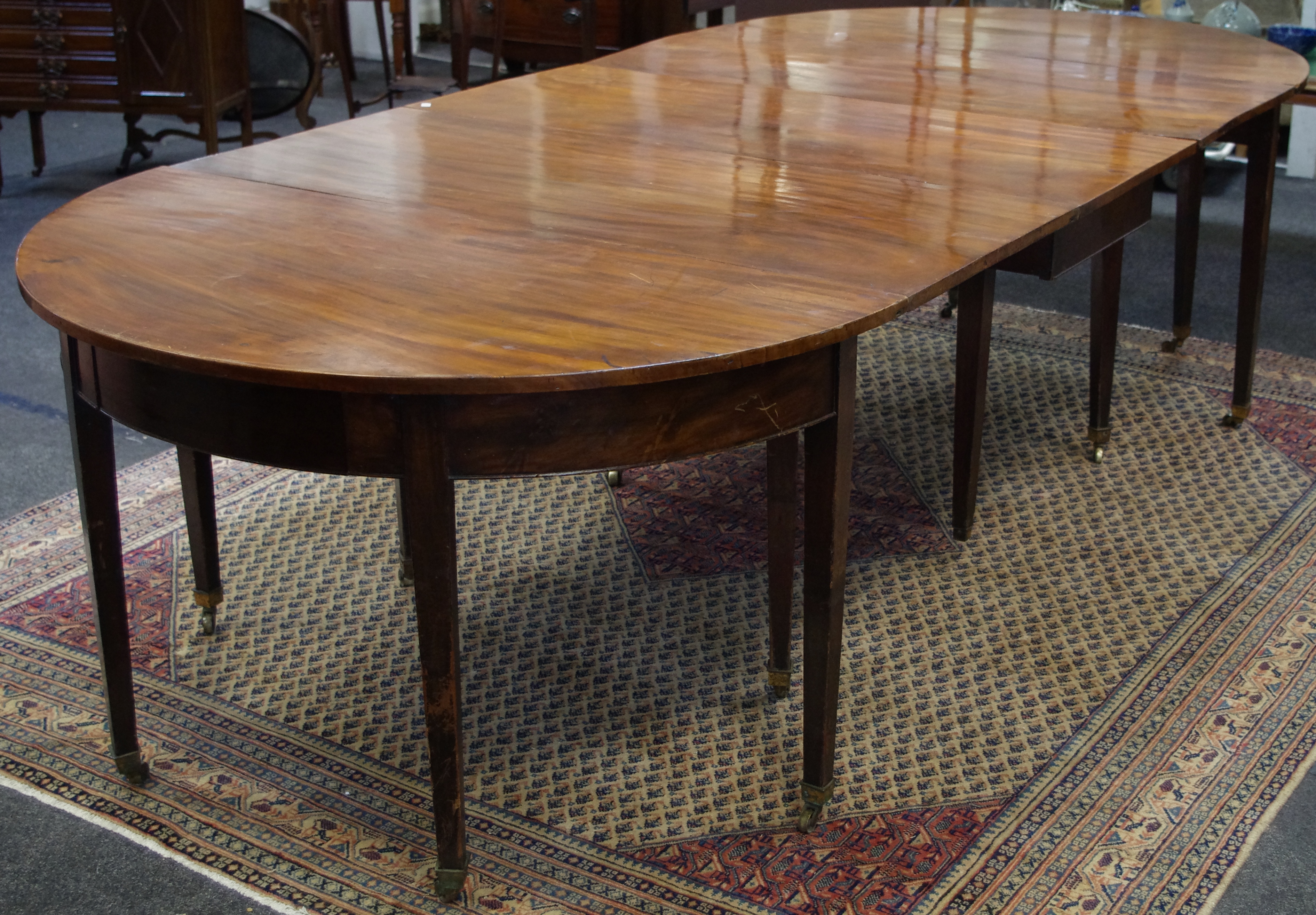 A George III mahogany dining table, formed from a central rectangular gateleg,
