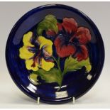 A Moorcroft Hibiscus pattern circular plate, tube lined with large red and yellow flowerheads,
