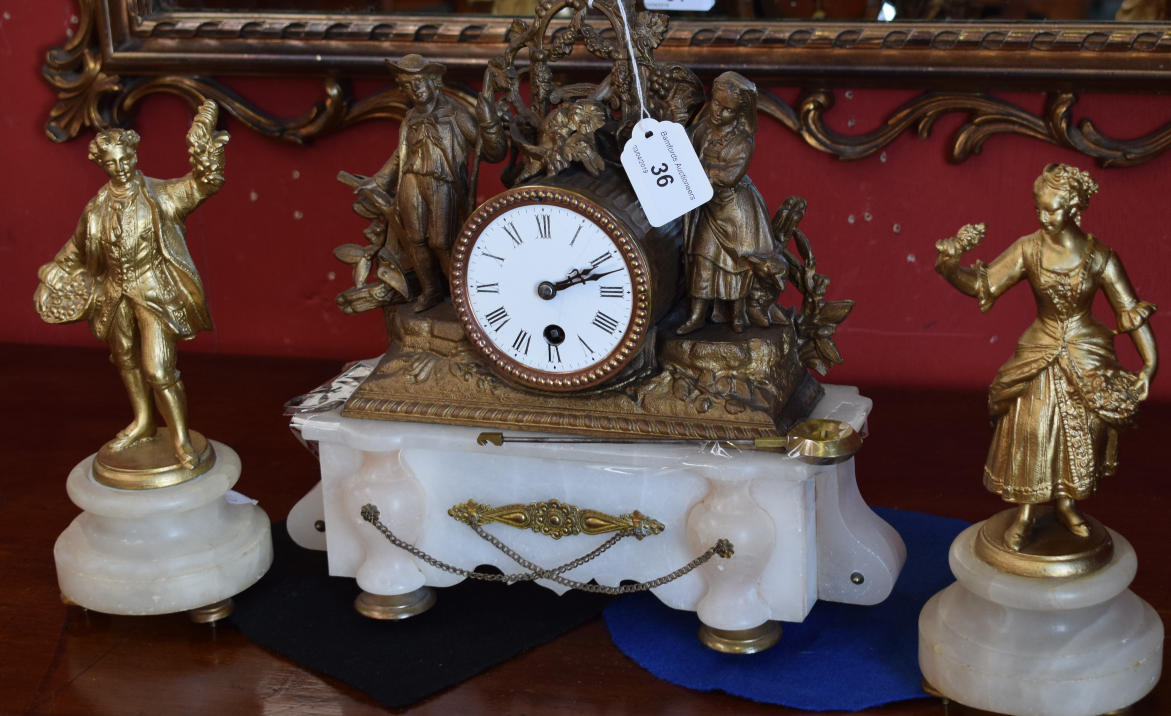 A 19th century matched gilt metal and alabaster three piece clock garniture, spelter figure case,