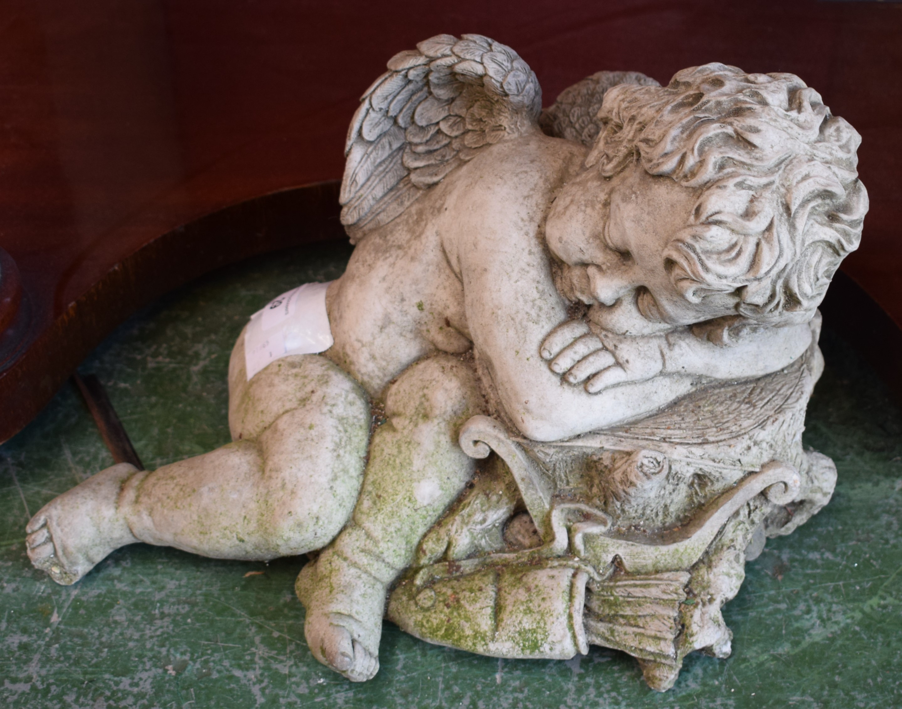 A contemporary composite garden ornament, of a sleeping cherub,