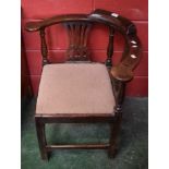 A late 19th/early 20th century oak corner elbow chair, curved cresting rail,