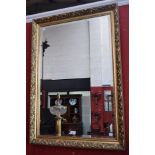 An ornate 'gilt' framed wall mirror, the rectangular frame applied with scrolling foliage,