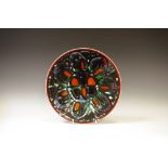 A Poole Pottery Adelphis bowl, decorated with a black, burnt orange and green seven petal flower,