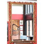 A Rococo style wall mirror, the rectangular frame applied with scrolling foliage, rope-twist border,