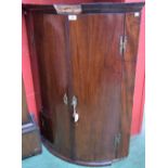 A George III mahogany bow-fronted wall hanging corner cupboard,