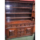 A Jacobean Revival oak dresser, outswept cornice above three plate racks,