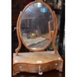 A George III mahogany dressing mirror, oval plate flanked by scrolling supports,