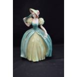 A Goebel model of a fashionable lady, she stands in green poke bonnet and dress holding a purse,
