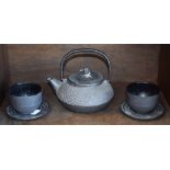 A Canadian iron tea kettle and two tea bowls and saucers,