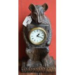 A 20th century Black Forest style bear clock, carved as seated, holding the clock dial to his chest,