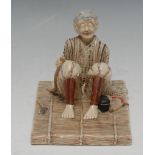 A Japanese Satsuma model, of a seated elder, the tools of his trade at his side,