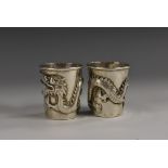 A pair of Chinese silver tapered cylindrical whisky tots, each applied with a ferocious, 4.