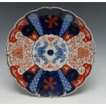 A Japanese Mosaic pattern fluted circular dish, painted in the Imari palette with mons,