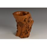 A Chinese rootwood libation vessel, carved in relief with blossoming prunus and pines, 10.