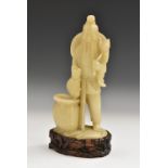 A Chinese soapstone carving, of a fisherman, he stands holding his catch, carved hardwood stand, 24.