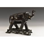 A 19th century Chinese ebony carving, of an elephant, emaciated back and ribs, inset glass eyes,