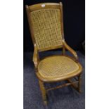 A Late Victorian elm rocking chair with cane work back and seat.