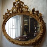 A large oval wall mirror, gilt wood and gesso frame.
