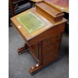 An oak piano top davenport, leather inlaid slope, four drawers, brass drum handles, brass castors.